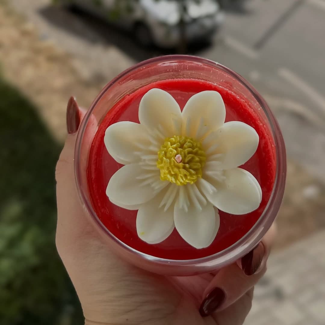 Qiri aromatik në gotë me lule qiriri sipër
